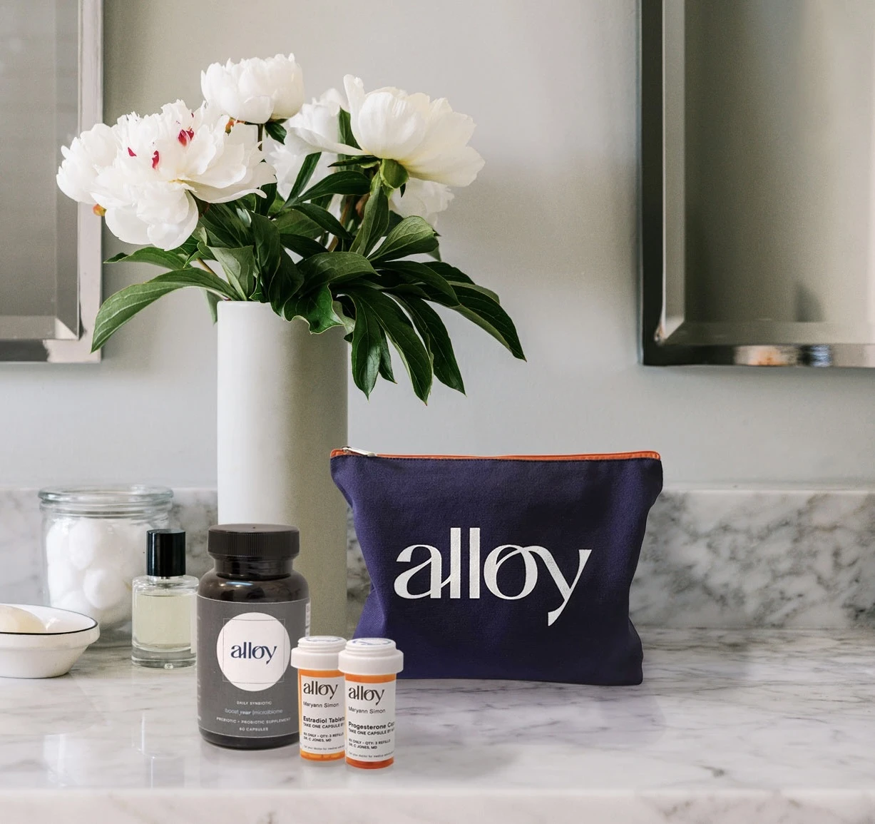 Alloy products on a marble counter next to a vase of white flowers