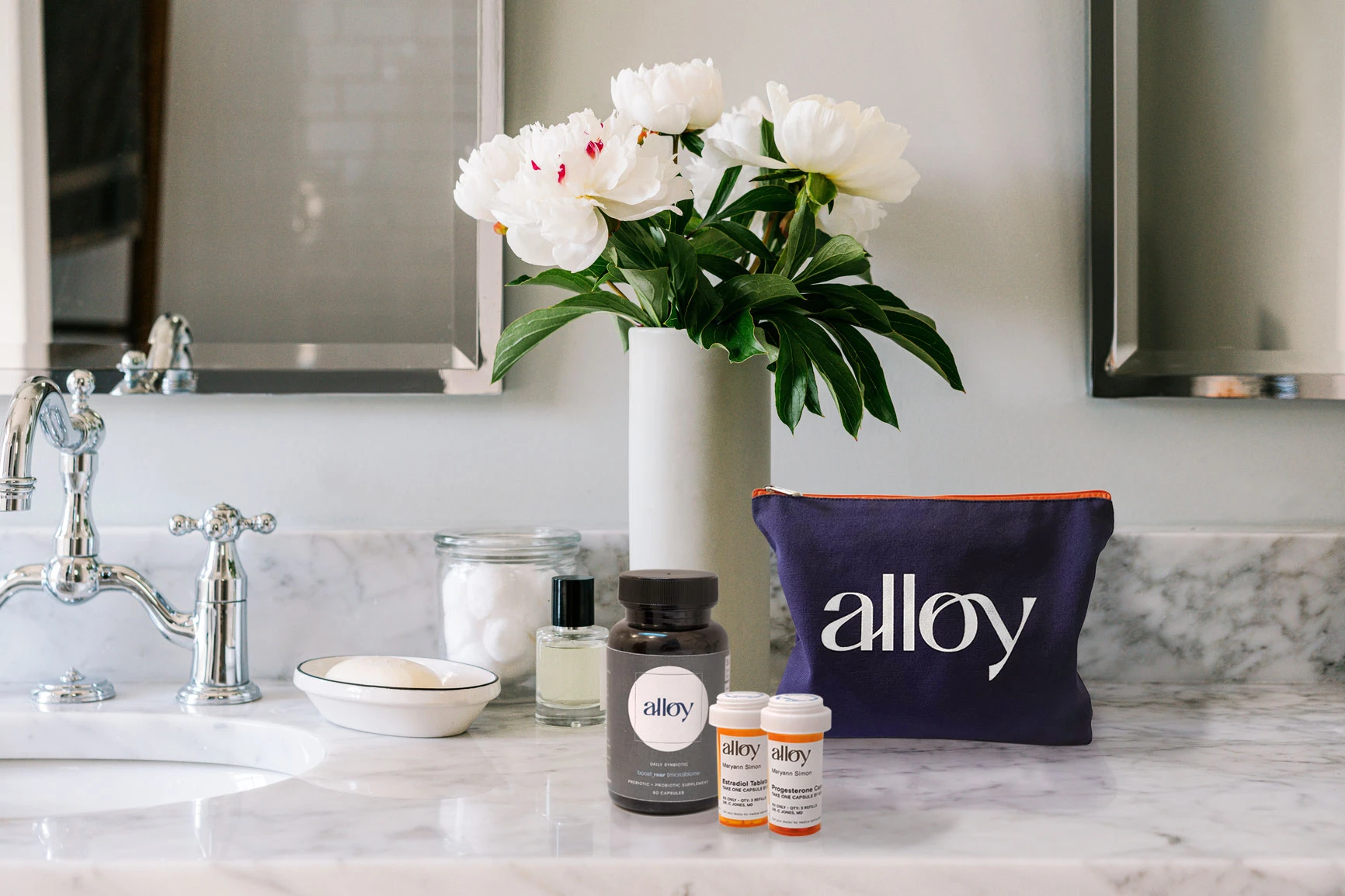 Alloy products on a marble counter next to a vase of white flowers