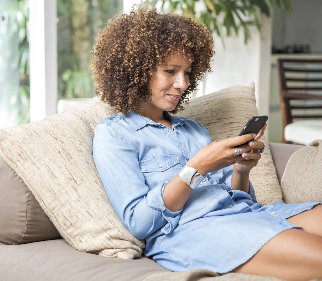 Woman leisurely sitting on couch looking at phone